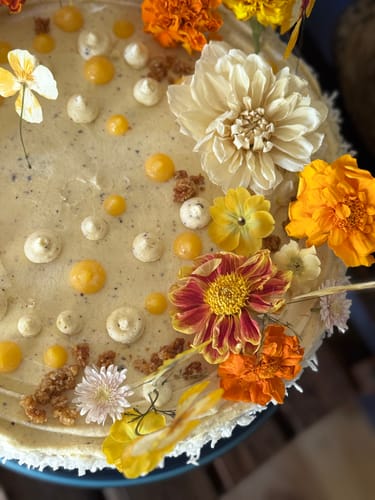 Customer's cake decorated with colorful, edible Bespoke Bloomish Box flowers on a windy day
