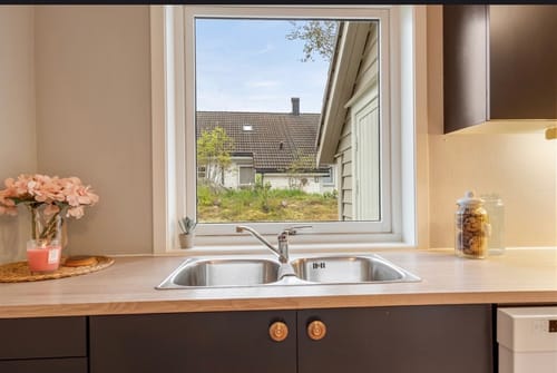 Customer's Oak minimal kontaktplast på en kjøkkenbenk med vask og utsikt gjennom vinduet.