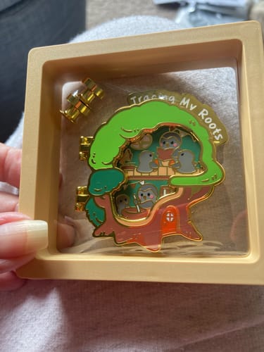 Customer's Tracing My Roots pin and magnet inside its beige magnetic display case held in a hand.