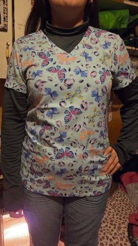 Customer's Koi 1122PRA top with blue butterfly print, worn over a dark grey long-sleeve shirt.