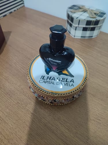 Customer's Attracione Sensual perfume, a black heart-shaped bottle, sitting on top of a decorative Ilhabela container.