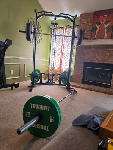 Customer's RitFit Smith Machine set up in a home room with green walls, featuring green weight plates and a barbell.