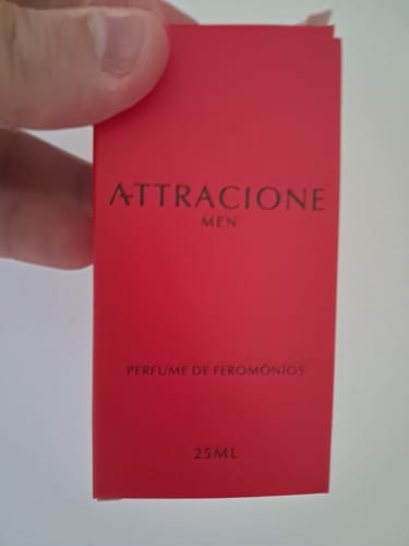 Customer's hand holding a red rectangular box of Attracione Men pheromone perfume.