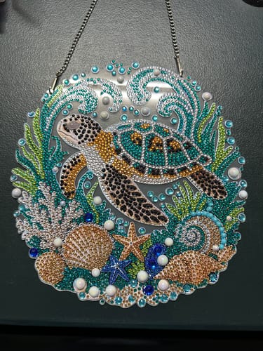 Customer's completed sea turtle diamond art hanging ornament with a metal chain, featuring sparkling colorful beads.