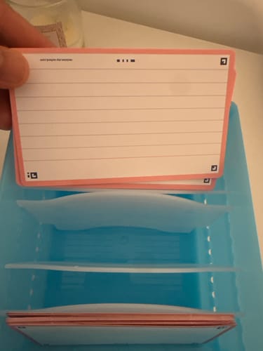 Customer's Flashcards FLASH 2.0 held by a hand over a light blue plastic organizer box