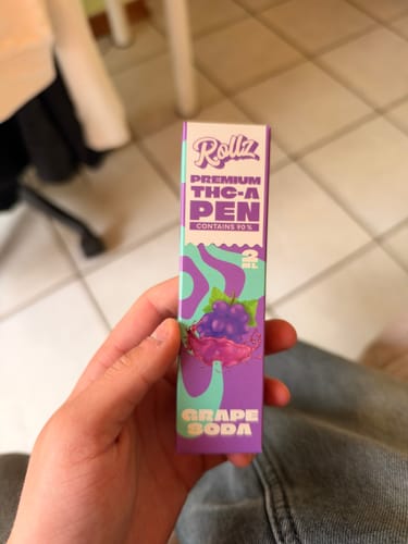 Customer's hand holding a purple Rollz THCA Vape box with Grape Soda label text.