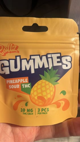 Customer's yellow pineapple-themed ROLLZ THC Gummies pouch held in a hand.
