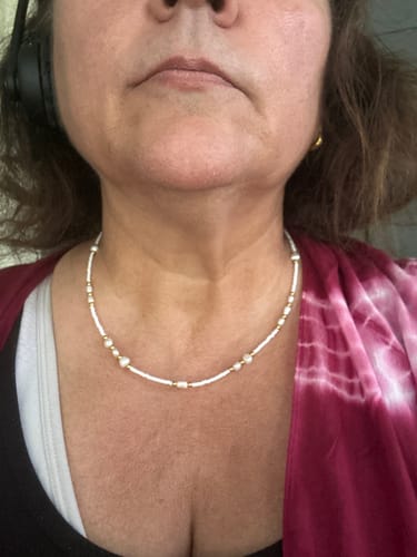 Customer's white beaded Fiji Necklace with gold accents worn around the neck.