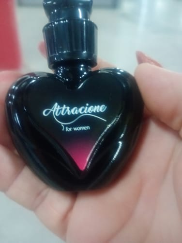 Customer's Attracione Sensual perfume held in a hand, featuring a small, heart-shaped black bottle.