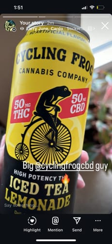 Customer's hand holding a bright yellow can of Cycling Frog Iced Tea Lemonade.
