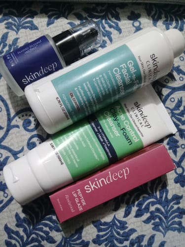 Customer's Acne Control Clay-to-Foam Cleanser alongside other Skindeep skincare bottles on a blue patterned surface.