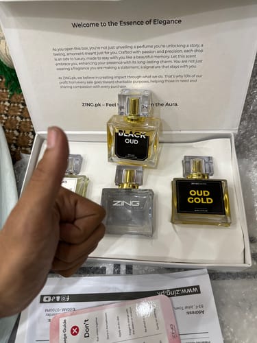 Reviewer's hand giving a thumbs up in front of an open OUD Supreme Bundle gift box containing three glass perfume bottles.