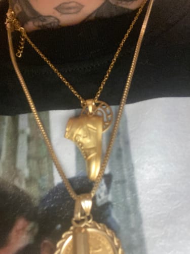 Customer's gold-toned shoe pendant necklace worn around the neck.