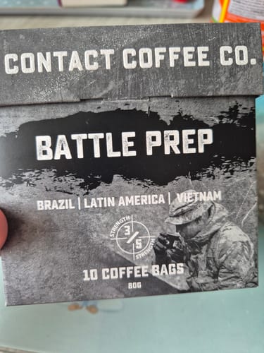 Customer's Battle Prep Coffee Bags box held in hand, showing gray camouflage design and product details.