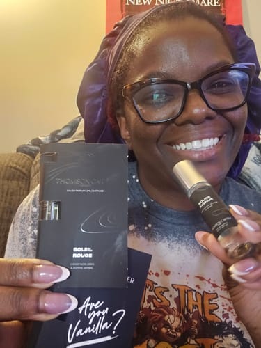 Customer's Soleil Rouge perfume sample vial and its black product card held in hand.