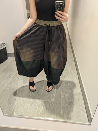 Customer's loose patchwork wide-leg jeans with a striped design, worn while standing in front of a mirror.