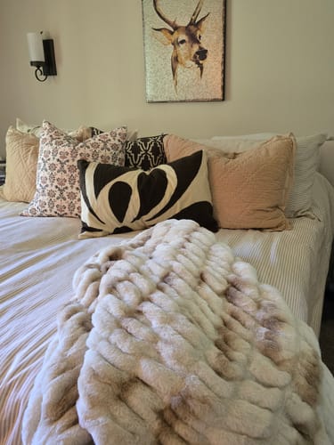 Customer's French Salt blanket draped over a bed with decorative pillows and wall art in a bedroom setting.