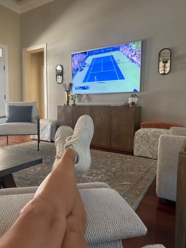Customer's white CUURT Muuv court shoes being worn while relaxing in a living room.