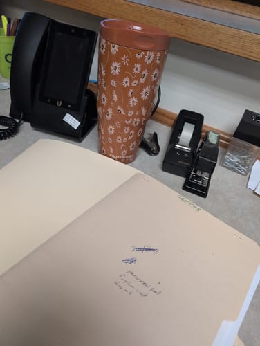 Customer's floral Sweet Daisy To-Go Buddy cup sitting on an office desk next to a phone and stapler.
