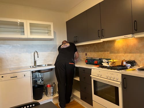Reviewer in kitchen, applying Uni matt antrasitt varm grå kontaktplast to cabinets