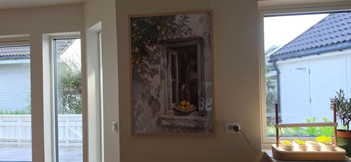 Customer's Making Lemonade art print hanging in a wooden frame on a living room wall near a window.