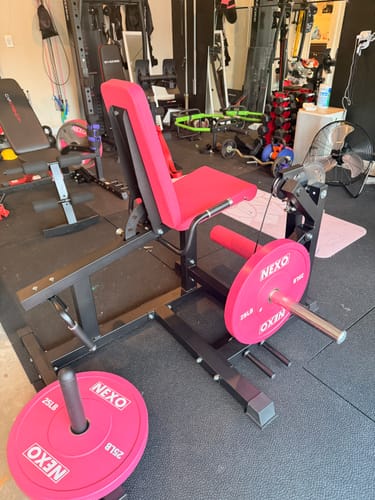 Customer's RitFit Leg Extension Curl Machine with pink weight plates in a home gym.