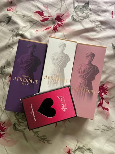 Customer's Kit Afrodite perfumes including three tall rectangular boxes and one pink heart-shaped box on a floral fabric.