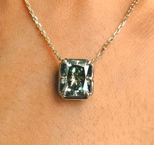 Customer's radiant cut midnight evergreen moissanite pendant necklace worn on a person's neck.