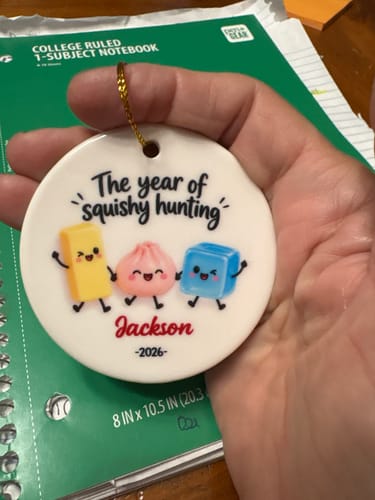 Customer's personalized The Year Of Squishies ceramic ornament held in a hand, featuring three cute characters.