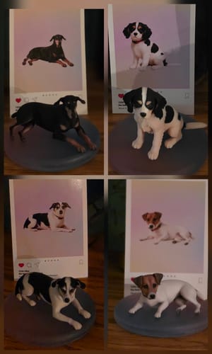 Reviewer's four custom 3D dog figurines on acrylic bases, showing heads tilted downward compared to reference photos.