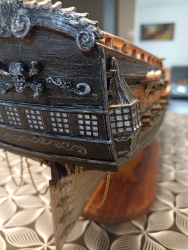 Customer's Royal Fortune maqueta, vista lateral cercana del casco de madera negra con detalle de calavera y tibias.