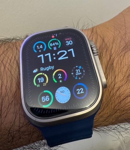 Reviewer's Apple Watch Ultra 2 with titanium case on wrist, showing a digital watch face with various data widgets.
