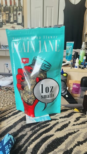 Customer's 1 Oz Cheap THCA Small Buds packaging with cyan and red label sitting on patterned fabric.