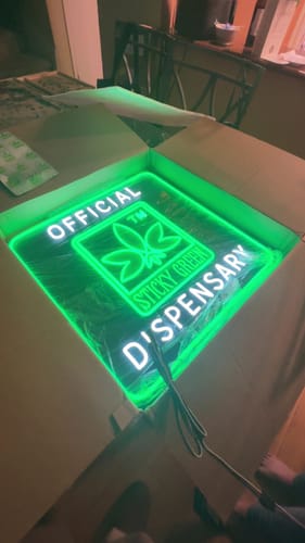 Customer's glowing green Sticky Green Neon Sign inside an open shipping box.