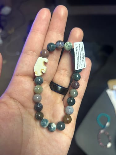 Customer's Mystery Bracelet with colorful beads and a white animal charm resting on a palm
