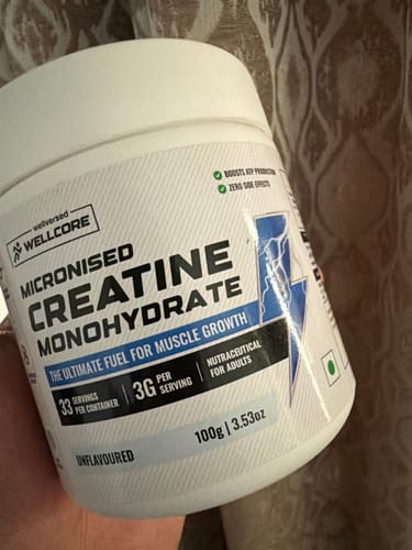 Customer's hand holding a 100g white jar of Wellcore Micronised Creatine Monohydrate.