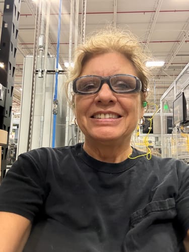 Customer smiling while at work, wearing safety glasses and protective earplugs, using the Micro Infusion System.
