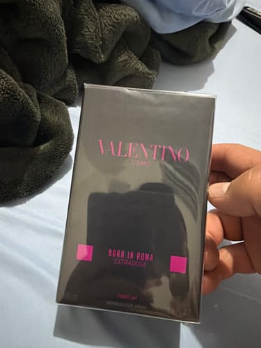 Customer's hand holding the black and pink Valentino Uomo Born in Roma Extradose parfum box.