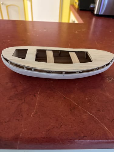 Customer's Maqueta Barco Calella wooden boat hull in progress on a reddish surface.