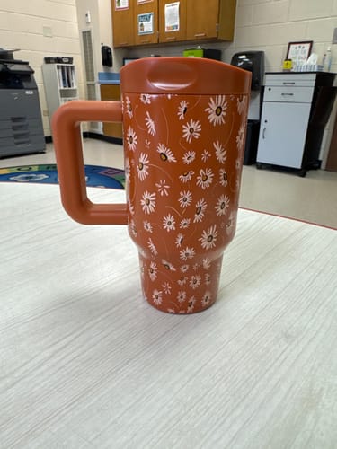 Reviewer's Sweet Daisy Mug Buddy with floral pattern standing on a table in an office setting.
