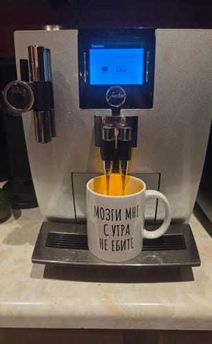 Customer's Mozgi glossy mug with Russian text placed under a coffee machine, filling with coffee.