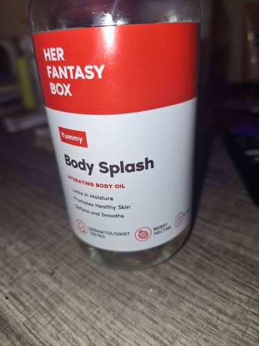 Customer's Yummy Body Splash hydrating body oil bottle sitting on a wooden surface.