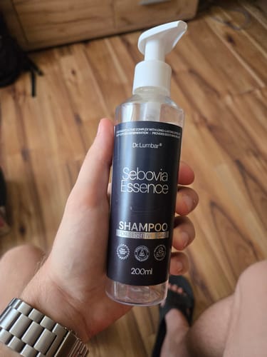 Customer's hand holding a bottle of Sebovia Essence shampoo, showing the black label.