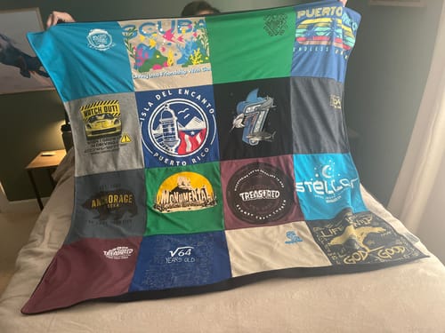 Customer's Project Repat T-Shirt Quilt held up, showing various colorful shirts in a multi-patch design.