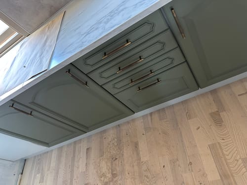 Customer's Stockholm håndtak bronse montert på olivengrønne kjøkkenfronter med en marmorert benkeplate.
