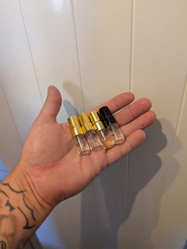 Kundenhand mit vier kleinen Tester Set 99cent Flakons mit goldfarbenen Verschlüssen.