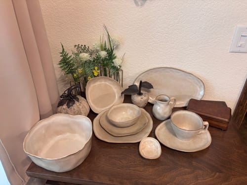 Customer's Crema Deep Organic Plate Set pieces, including bowls, cups, and plates on a wooden surface.