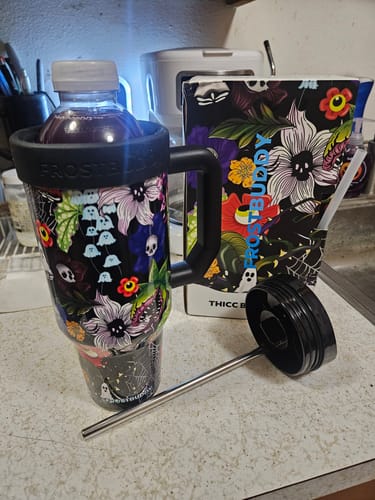Customer's Thicc Buddy mug in Toxic Bloom print holding a drink, with its matching floral box and straw nearby.