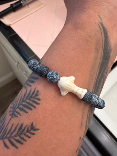 Customer's The Quest Bracelet on a tattooed wrist, showing the grey textured beads and whale shark charm.