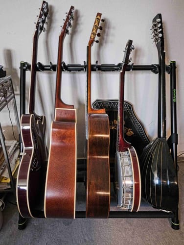 Kunden-Foto der Donner DJP-1000 Jazz E-Gitarre in einem Gitarrenständer neben vier anderen Instrumenten.